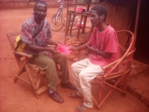 Photo 1: Client (in red T-shirt) being supported by a Health Worker from AIC Jinja to start TB initial phase